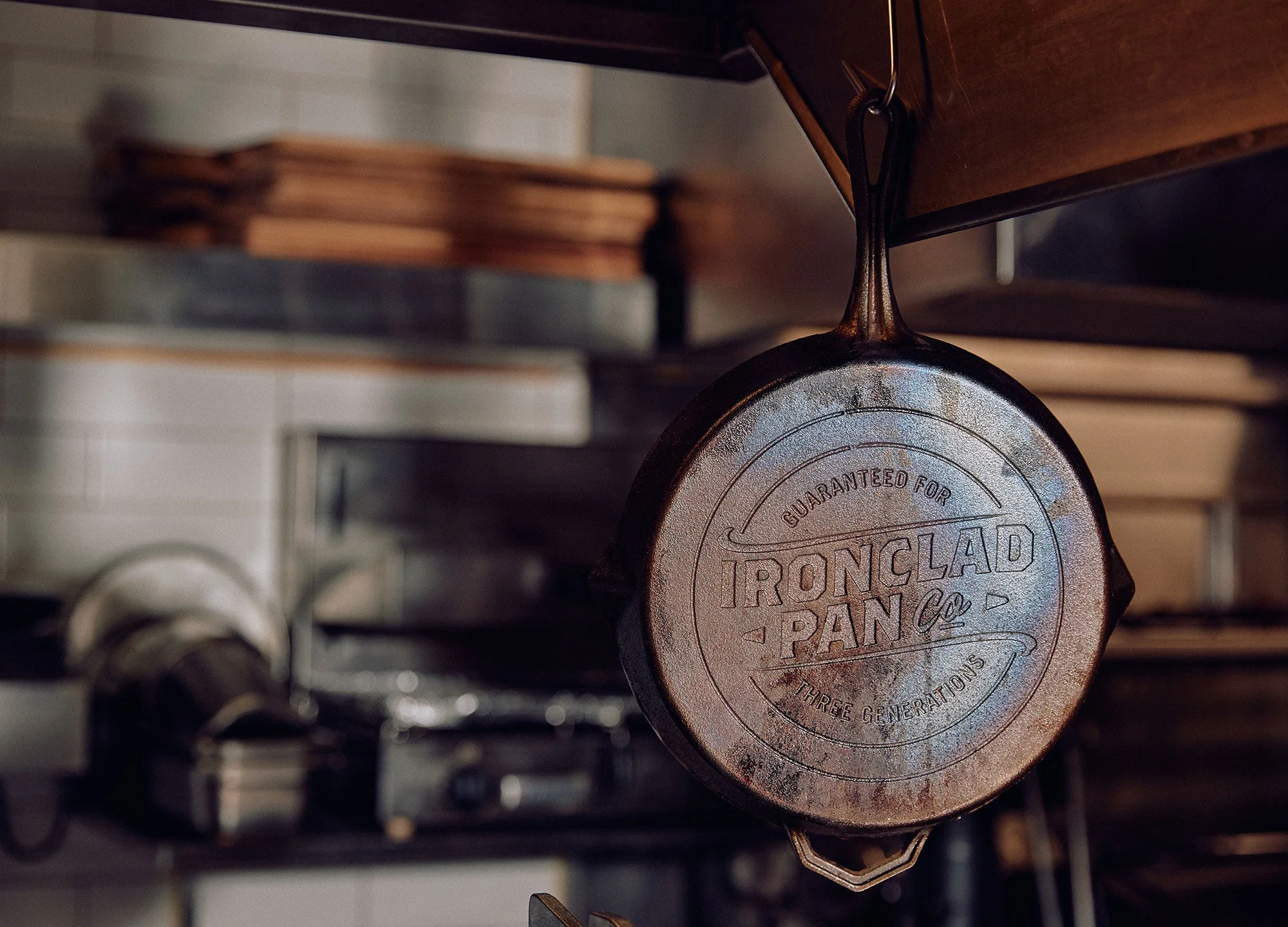 A seasoned Ironclad pan hanging by its handle in a kitchen